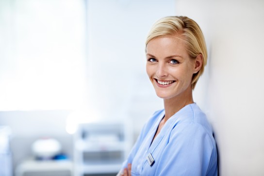 MFA lehnt an der Wand un lächelt