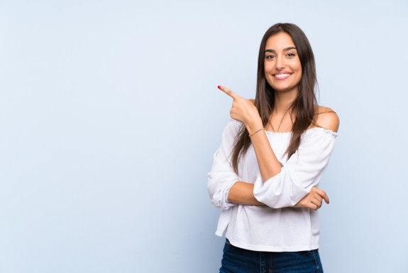 Junge Frau zeicht lachend in die linke, obere Ecke