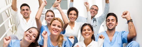 Praxispersonal sitzt jubelnd auf einer Treppe