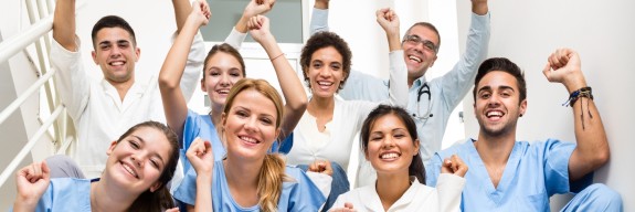 Praxispersonal sitzt jubelnd auf einer Treppe