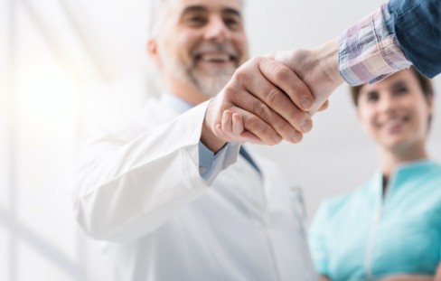 Arzt schüttelt Mann außerhalb des Fotos die Hand